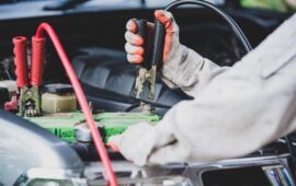 Car repairman wearing a white uniform standing and holding a wre